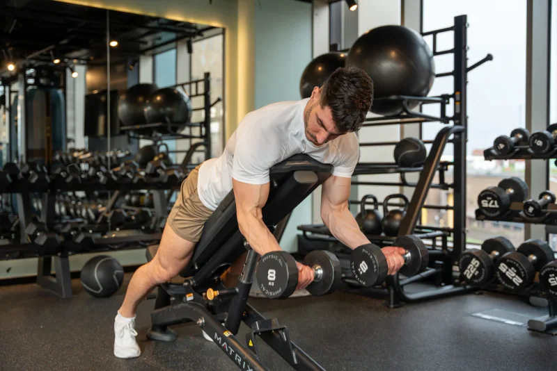 Atai training with dumbbells in a white T-shirt